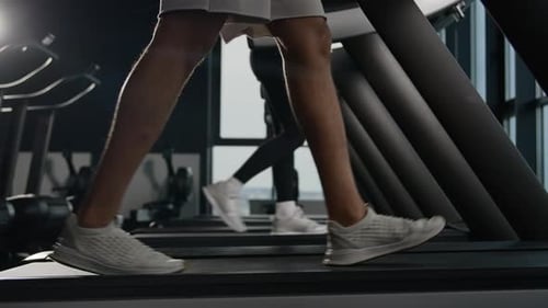 Side View Legs in Sneakers Walk on Treadmill in Fitness Gym Unknown Woman and Man Going Footstep