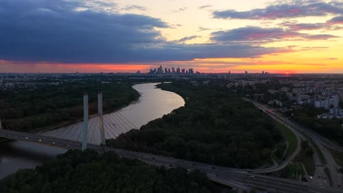 Aerial establishing shot of tranquil Vistula River, driving cars on Main Street in goclaw district
