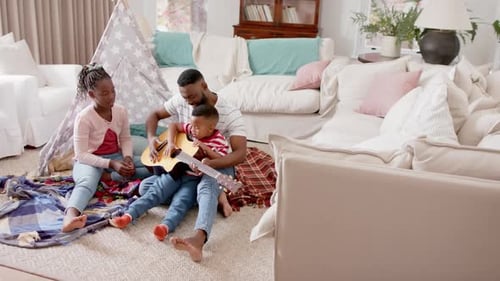 Father Plays Guitar with Children Indoors