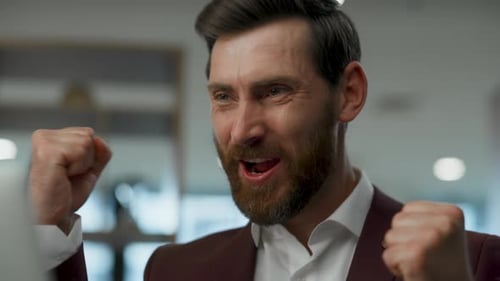 Excited man in suit pumps fists, office setting