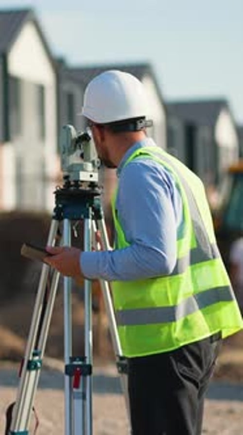 Surveyor Engineer Using Theodolite and Tablet at Construction Site