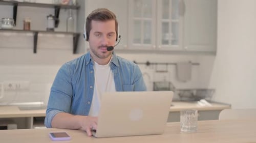 Young Man with Headset Looking toward Camera in Call Center