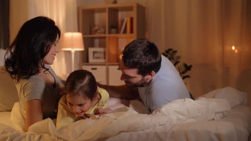 Happy family together in bed at nighttime