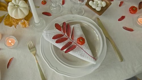 Branch with Red Leaves, Mini Pumpkin and White Napkin on Plate on Festive Table