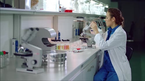 Woman in Lab Coat Using Microscope for Research