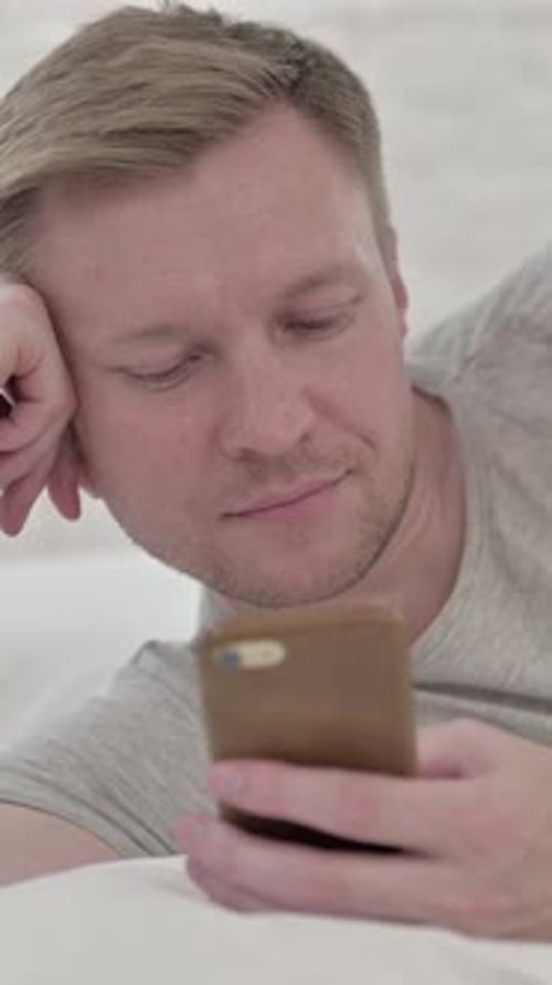 Close up of Man Using Smart Phone While in Bed, Vertical Video