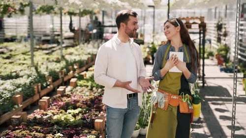 Man and Woman Talking in Greenhouse Among Plants