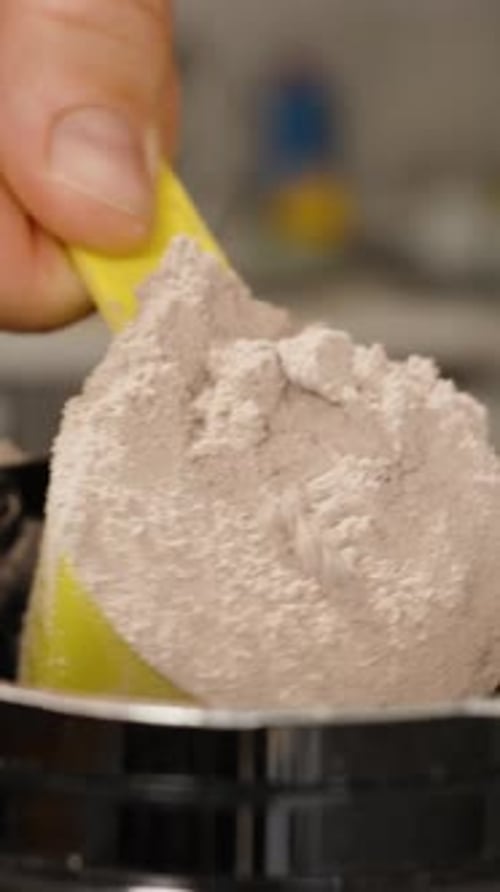 Vertical video. Man Scooping a Heaping Spoonful of Protein Powder, Tapping Off the Excess.
