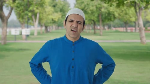 Sick Muslim man suffering from back pain in park