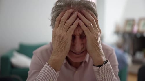 Senior man with hands covering face, expressing deep frustration and fatigue, emotional strain