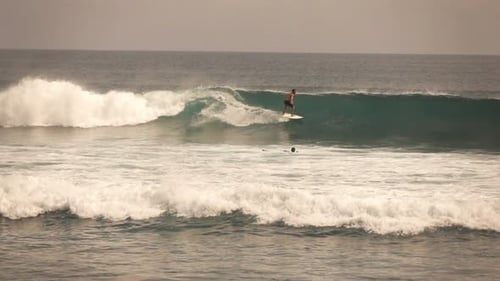 Man surfing a wave in the ocean rides the crest in super slow motion