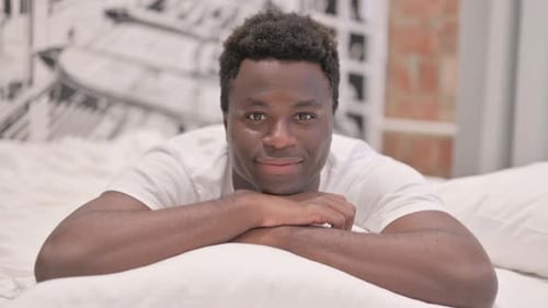 Pouce levé par un Afro-Américain allongé sur le ventre dans son lit
