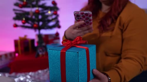 Woman Using Phone With Christmas Gift Present