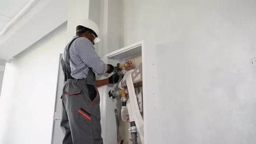 African American Plumber Installs or Inspects Fire Hydrant in Office