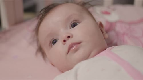 Cute Smiling Baby Girl Lying Awake in Her Crib