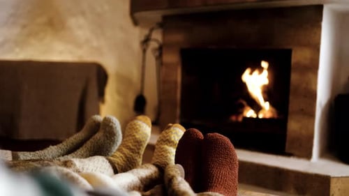 Feet in wool socks near fireplace in winter - Cozy christmas holiday home relaxation