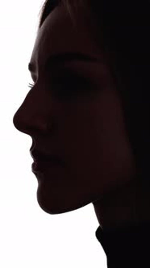Woman's face in shadow profile portrait against white