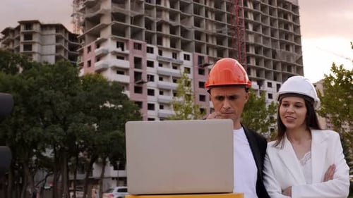 A Builder and an Architect with a Laptop are Standing at a Construction Site