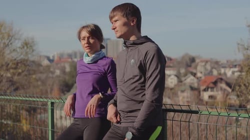 An Active Couple Pauses During Their Outdoor Workout Enjoying the City Panorama