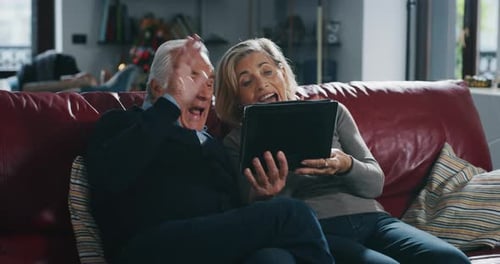 A happy mature senior couple is making a selfie or technology video call to their relatives with a