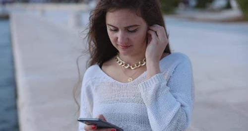 Woman Using Phone on Pier Near Ocean