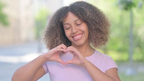 Young Woman Makes Heart Shape with Hands