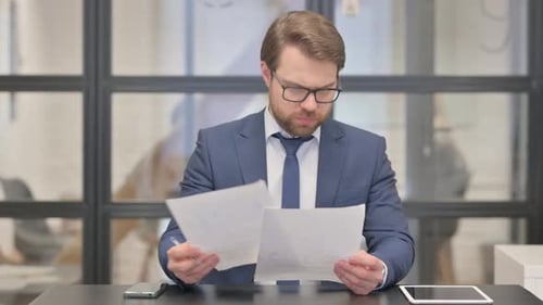 Man Reviews Documents in Modern Office Setting