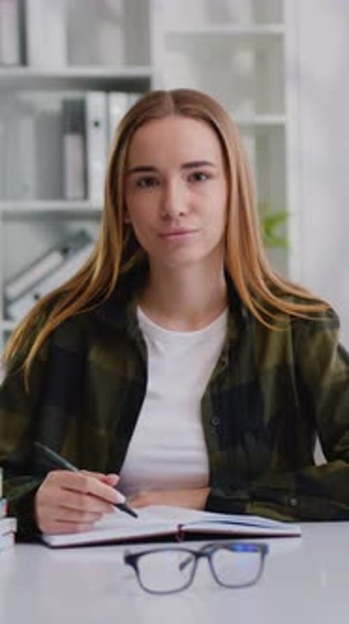 Woman Sitting at Desk with Notebook and Pen