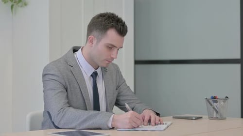 Young Adult Taking Notes in Modern Office