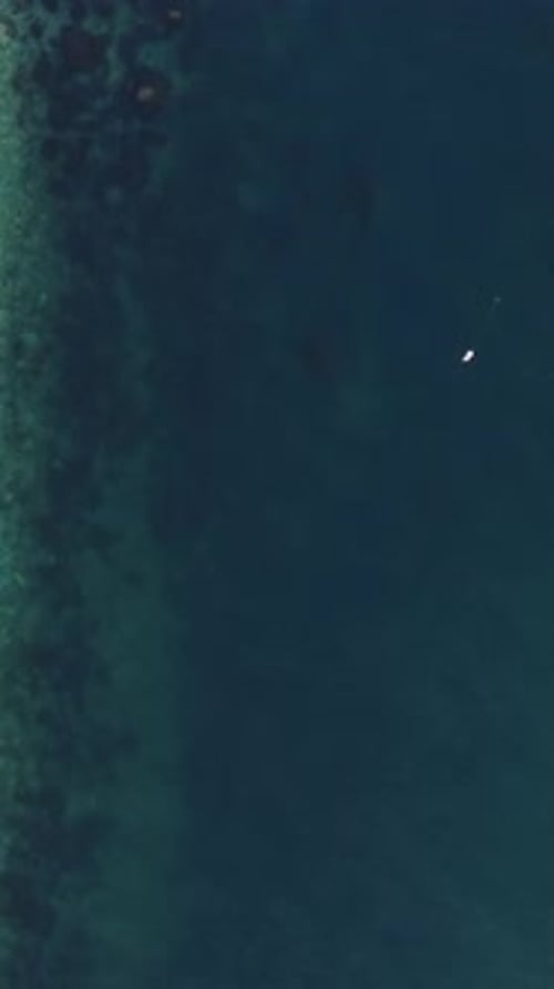 Aerial Vertical View of Beach with Wave Caressing Shore Sun Glare Small Waves on the Water Surface