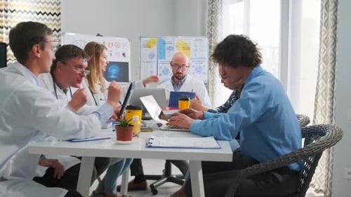 Doctors Discussing Reports with Laptops at Hospital Seminar