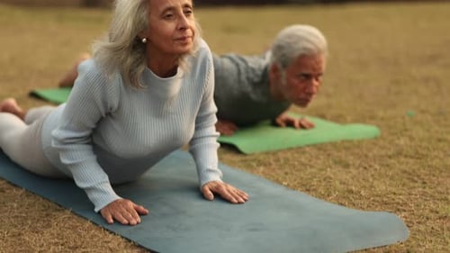 Senior Couple Practicing Yoga Outdoors on Exercise Mats