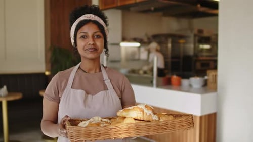 Portrait of Happy Woman Holding Tray of Croissants in Bakery