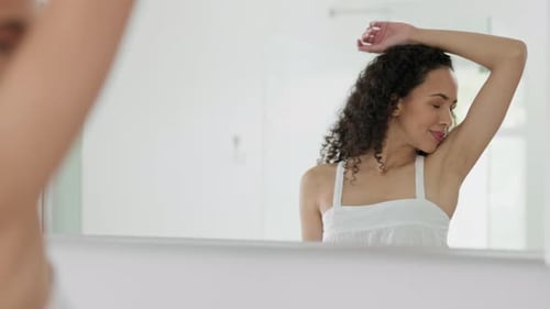 Young Woman Styling Hair in Bathroom Mirror
