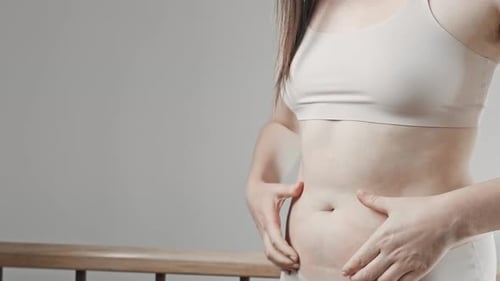 Une femme en sous-vêtements blancs tient ses grosses hanches.
