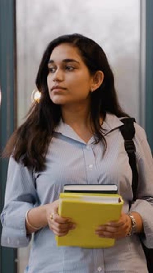 Young Indian Student Holding Books and Backpack in College Hallway