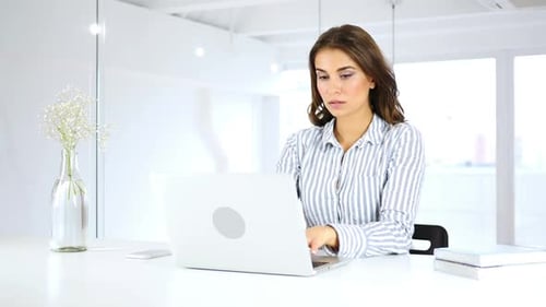 Young Woman Working on Laptop in Bright Office