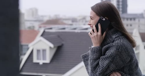 Woman Talking on Phone on Balcony in City
