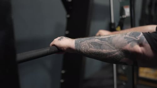 Young man prepares for lift on barbell inside modern indoor gym setting