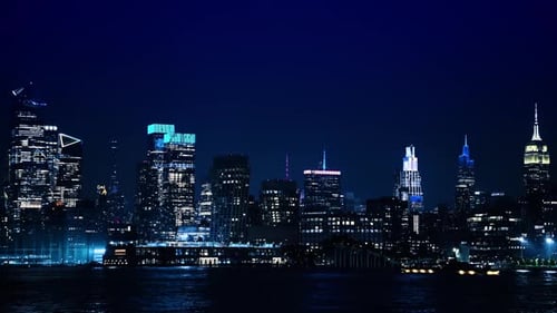 Long cruise boat moves by the East River near the Pier 55. Luminous skyline of New York