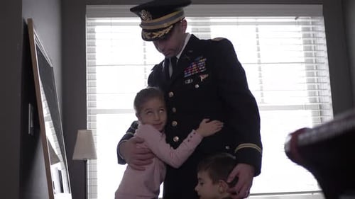 Soldier hugs his children in home interior