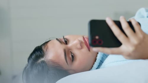 Dark Haired Woman Using Phone in Bed