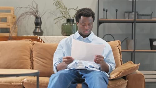Adult Man Reads Documents on Couch