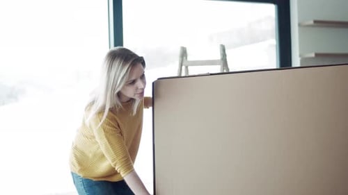 Woman Moving Large Cardboard Box Inside New Home