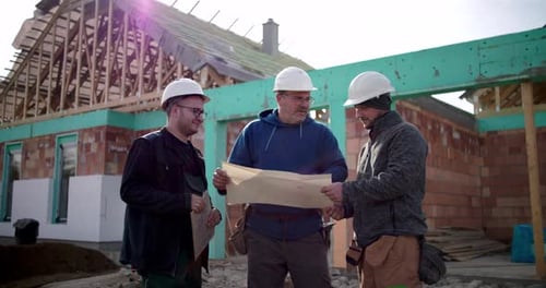Construction Workers Reviewing Blueprints at Construction Site