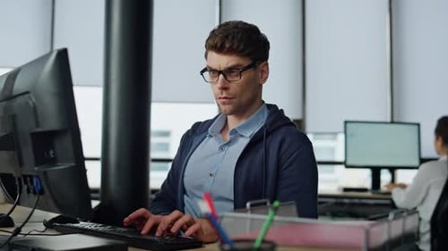 Serious it guy typing computer in modern office data center optimizing software
