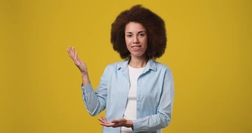 Woman Presenting and Pointing on a Yellow Background