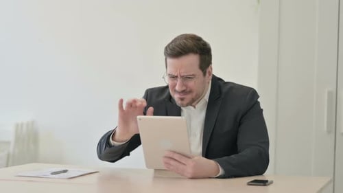 Frustrated Businessman Using Tablet in Office