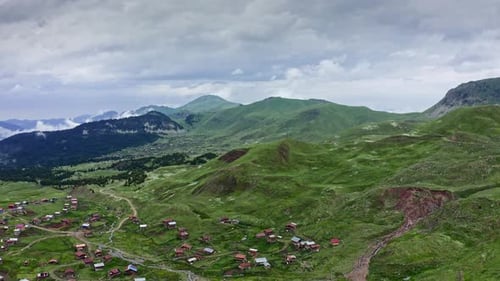 Flight Over Mountain Plateau With Villages And Woodlands On Moody Summer Day