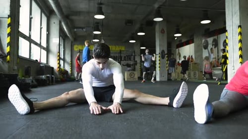 Young People in Crossfit Gym Stretching Their Legs